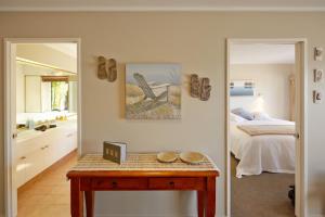 a bedroom with a bed and a table and a bathroom at Pioneer Waterfront Apartments in Paihia