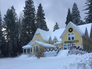 McCloud的住宿－McCloud River Bed and Breakfast，一座黄色的房子,地面上积雪