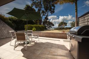 a table and chairs with an umbrella and a grill at Pioneer Waterfront Apartments in Paihia