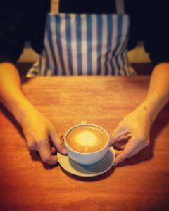 una persona seduta a un tavolo con una tazza di caffè di TK residence a Kalasin