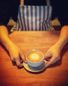 a person sitting at a table with a cup of coffee at TK residence in Kalasin