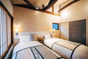 2 camas en una habitación con ventana en MINKA Riverside Villas, en Shimminato