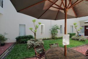 a wooden table with an umbrella in a yard at Polamas Residence Padang in Padang