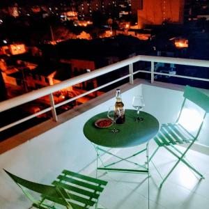 uma mesa e cadeiras numa varanda com uma garrafa e copos em Soles de Salta dpto, cochera, balcón a 600m de plaza principal em Salta