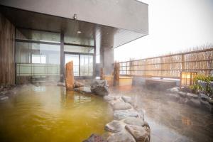 富良野La Vista Furano Hills Natural Hot Spring的大楼内带水池的房间