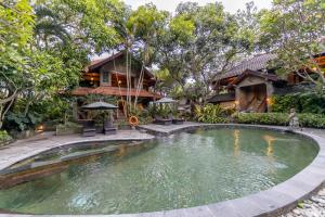 a swimming pool in front of a house at De Munut Balinese Resort in Ubud