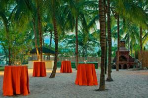 two tables with candles on them on a beach with palm trees at Abuja Continental Hotel in Abuja