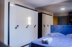 a bedroom with a blue bed with a large window at Apartamento aconchegante em frente ao Shopping JL in Cascavel