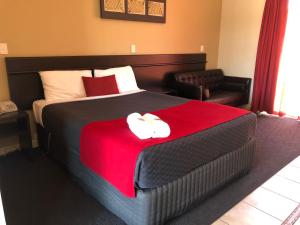 a bedroom with a bed with a red blanket and two slippers at Collie Ridge Resort in Collie