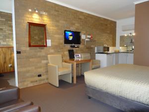 1 dormitorio con 1 cama y escritorio con TV en Peppinella Motel, en Ballarat