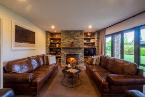 uma sala de estar com sofás de couro e uma lareira em Lime Tree Lodge em Wanaka