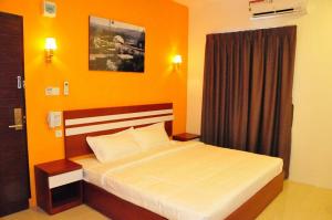 a bedroom with a bed with an orange wall at Venia Hotel Batam - CHSE Certified in Sagulung +8 photos