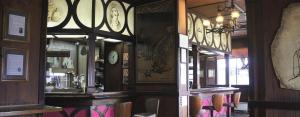 a restaurant with a bar with clocks on the walls at Moruya Monarch Hotel in Moruya