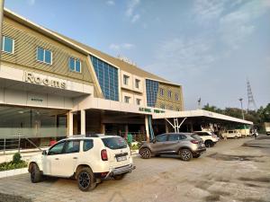 two cars parked in a parking lot in front of a building at HOTEL SAHYOG & ROOMS in Surat