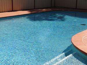 a large swimming pool with blue water at Peppinella Motel in Ballarat