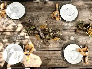 uma mesa de madeira com pratos brancos e copos de vinho em La Saracina em Pienza