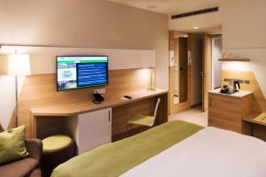 a hotel room with a bed, desk and television at Holiday Inn Frankfurt Airport, an IHG Hotel in Frankfurt/Main