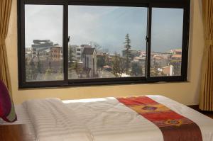 a bed in a room with a large window at Sapa Sunrise Hotel in Sapa