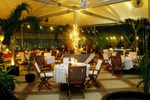 un ristorante con tavoli e sedie bianchi e luci di Grand Arkenso Park View a Semarang