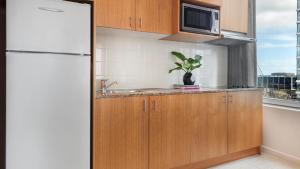 a kitchen with a refrigerator, sink, and dishwasher at Oaks Melbourne on Market Hotel in Melbourne