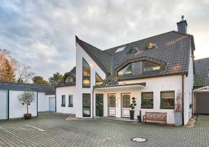een wit huis met een zwart dak bij Hotel Zur Krone in Meerbusch