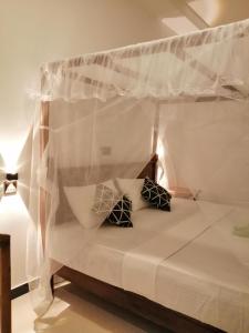 a bed with a canopy with two pillows on it at Temple Tree Mirissa in Mirissa