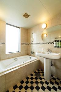 a bathroom with a bath tub and a sink at Nest Hotel Sapporo Odori in Sapporo