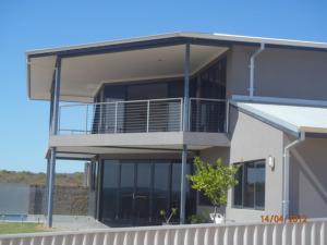 a large building with a balcony and a tree at Eco Haven retreat in Kalbarri