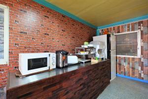 a kitchen with a microwave and a brick wall at Phuket Numnoi in Bang Tao Beach