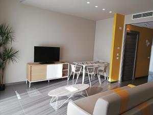 een woonkamer met een bank, een tafel en een televisie bij Ciclope Resort in Acitrezza