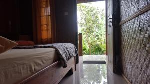 1 dormitorio con 1 cama y puerta abierta en Tetebatu Indah Homestay en Tetebatu
