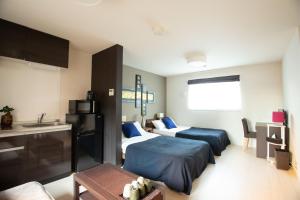 une chambre d'hôtel avec deux lits et une cuisine dans l'établissement Apartment Hotel STAY THE OSAKA, à Izumi-Sano