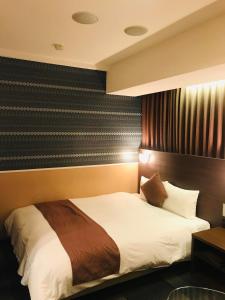 a bedroom with a large bed with white sheets at Sejour Inn Nagarekawa in Hiroshima