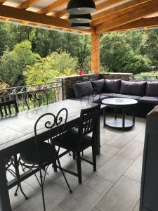 eine Terrasse mit einem Tisch, Stühlen und einem Sofa in der Unterkunft Au bord de l eau in Surba