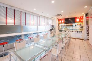 a restaurant with glass tables and white chairs at Sejour Inn Nagarekawa in Hiroshima