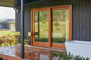 a patio with a glass door and a table and chairs at Studio 40 in Coromandel Town