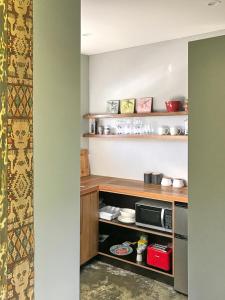 a kitchen with wooden shelves and a microwave at Studio 40 in Coromandel Town