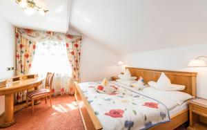a bedroom with a bed and a desk at Romantik Hotel & Restaurant Stafler in Vipiteno