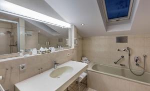 a bathroom with a sink and a tub and a mirror at Landgasthaus & Hotel Kurfer Hof in Bad Endorf