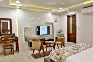Una habitación de hotel con una cama, un escritorio y un televisor. en Marigold Inn- Homestay, en Jaipur