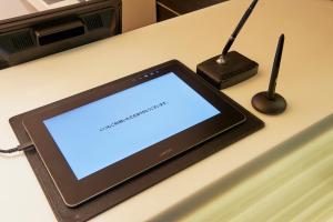 a tablet sitting on a desk with a blue screen at Sotetsu Fresa Inn Higashi Shinjuku in Tokyo
