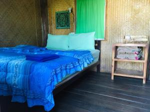 a bed with a blue comforter in a room at Golden Hut -Chill Bungalows in town黄金泰式传统独栋小屋 in Pai
