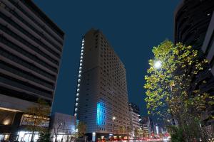 a tall building with lights on it in a city at Sotetsu Fresa Inn Higashi Shinjuku in Tokyo