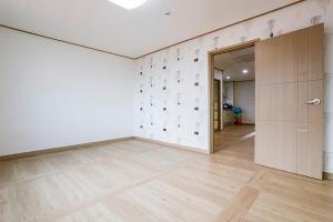 an empty room with white walls and wooden floors at Jeju Special Pension in Jeju