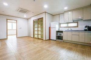 a large kitchen with white cabinets and a wooden floor at Jeju Special Pension in Jeju