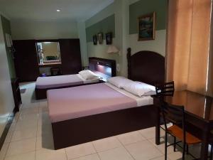 a bedroom with two beds and a table and a desk at ROLET HOTEL in Catbalogan