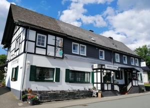 ein schwarzweißes Gebäude mit grünen Fensterläden in der Unterkunft Hildfelder Stübchen in Winterberg