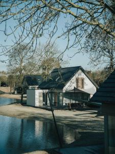 een wit huis met een zwart dak naast een meer bij Ridderstee Ouddorp Duin in Ouddorp