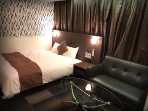a hotel room with a bed and a couch and a glass table at Sejour Inn Nagarekawa in Hiroshima