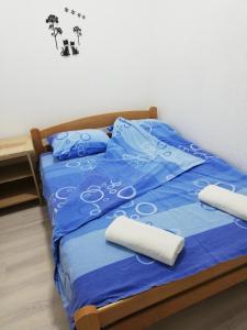 a bed with blue comforter and two pillows at Kopaonik Apartman Aleksandar in Kopaonik